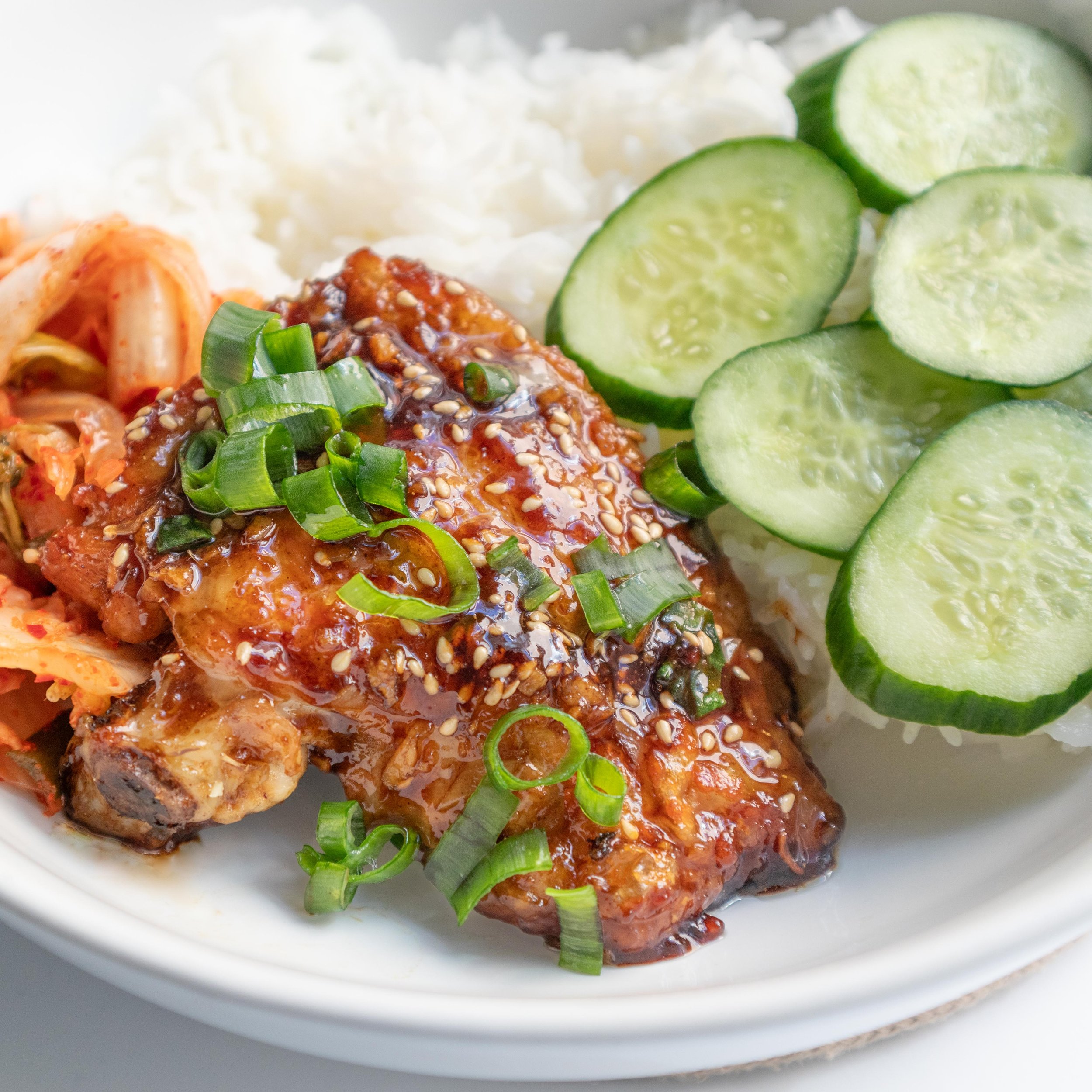 Pan-fried soy sauce glazed chicken served with fresh cucumber slices, steamed rice and kimchi.