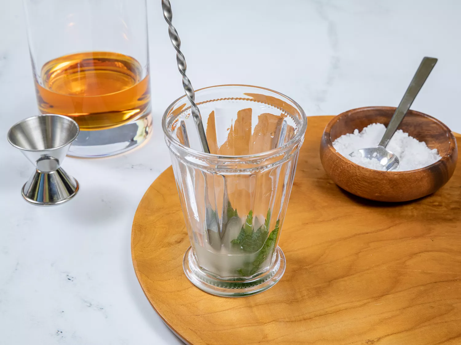 muddling mint leaves, sugar, and water in mint julep glass